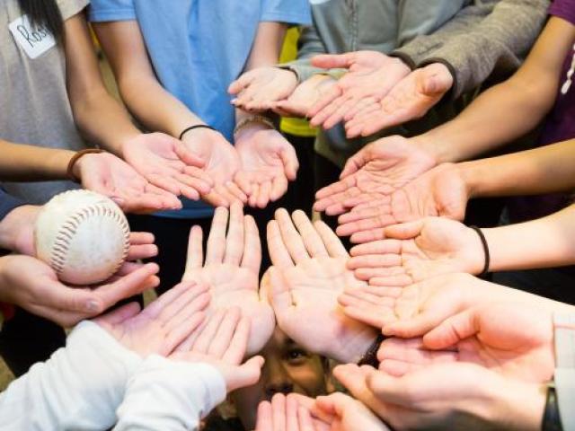 students' hands facing up and one of them holding a ball